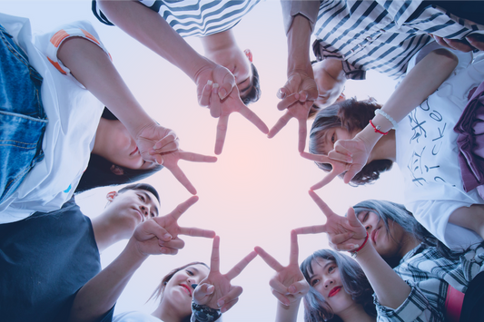 Friends gathered together outdoors, forming a heart shape with their hands